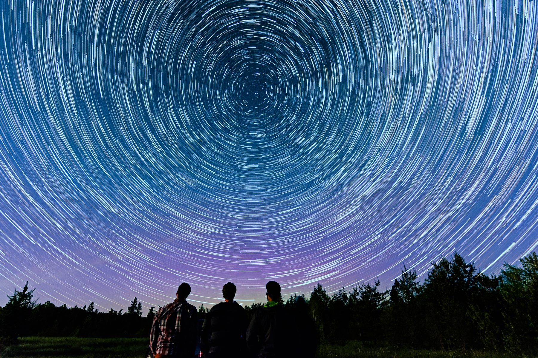 Friends light-painting a ring under a full sky of stars