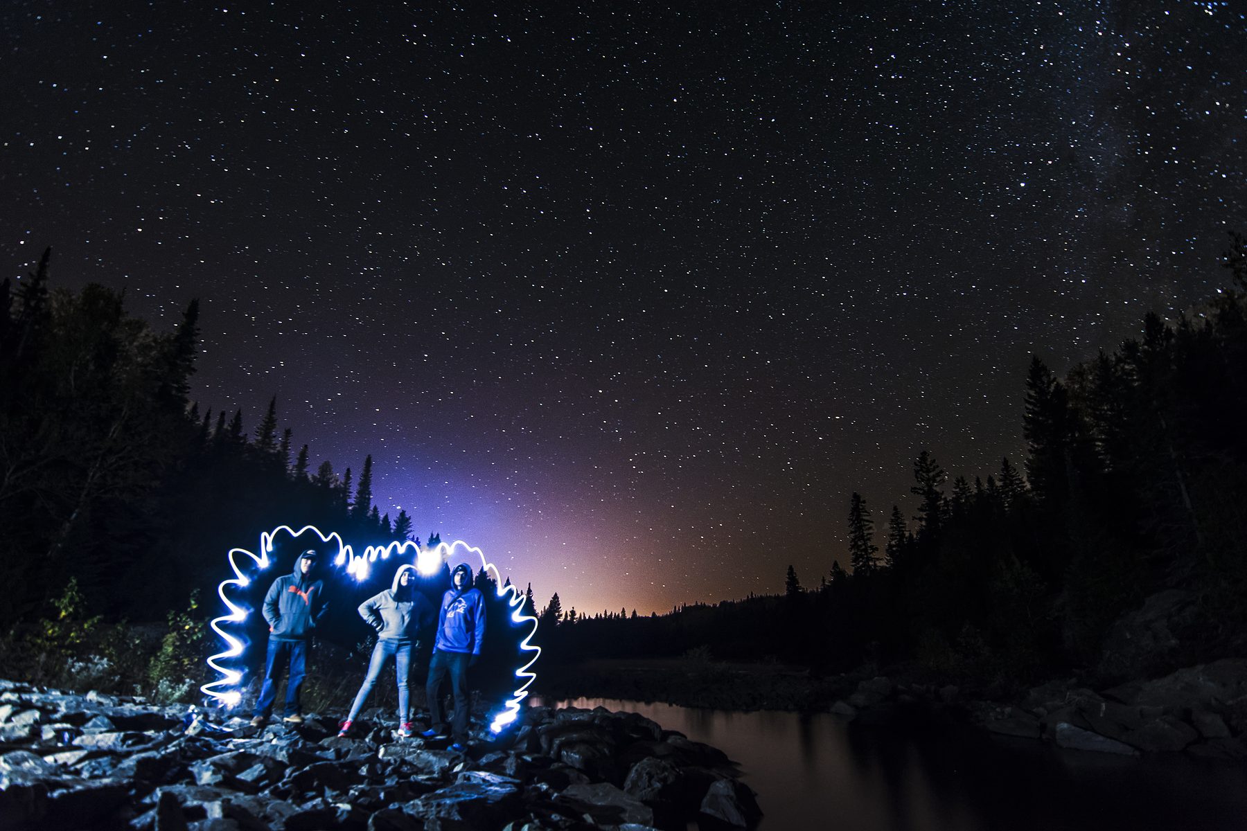 A lit tent beneath streaking star trails