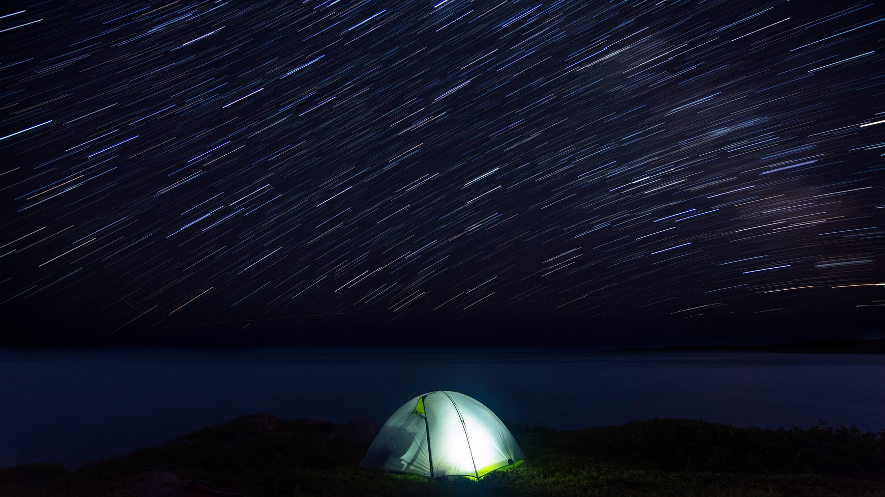 A flashlight raised to the Milky Way over the lake