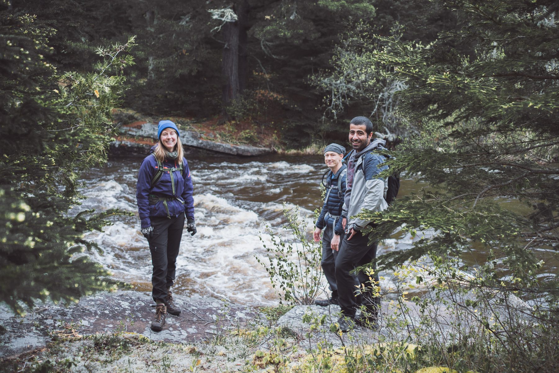 The group pauses along the rushing river below the falls
