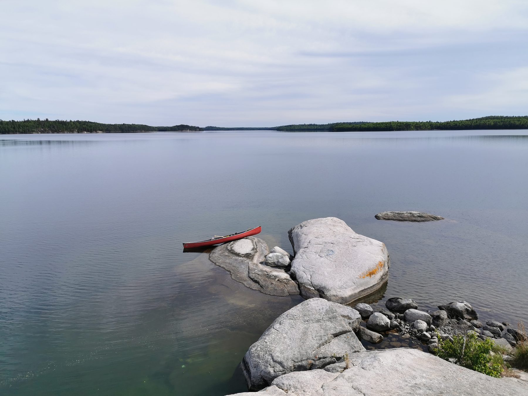 The canoe pulled up on the shoreline rock